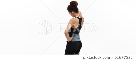 Healthy and Fitness concept - portrait of African American girl suffers a muscle injury standing holding her neck and lower back with back view. Isolated on white background. 91677583
