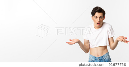 Lgbtq community. Confused gay man in crop top shrugging and staring at camera, cant understand, standing over white background 91677738