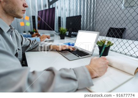 Man typing on laptop in the office 91677774