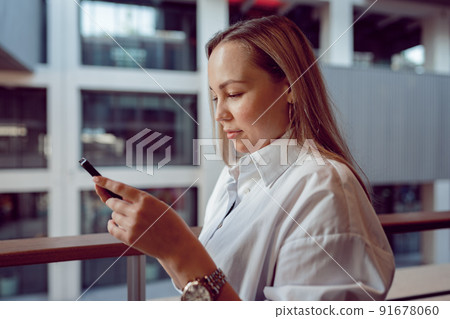 Businesswoman using her mobile phone in the balcony 91678060