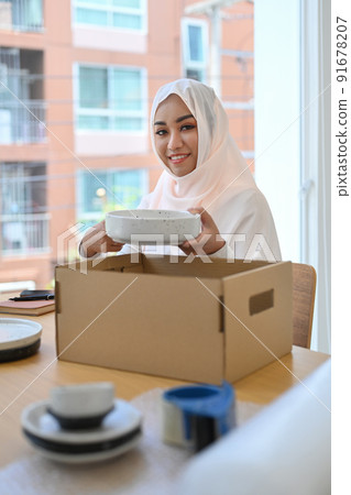 Beautiful Muslim woman in hijab preparing parcel boxes of product for shipping to customers Beautiful Muslim woman in hijab preparing parcel boxes of product for shipping to customers 91678207
