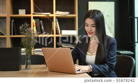 Pleasant asian businesswoman typing business email, searching information on her laptop computer Pleasant asian businesswoman typing business email, searching information on her laptop computer 91678242