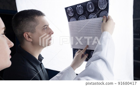 Epileptologist examines patient MRI and electroencephalogram. Concept treating epilepsy and helping people who suffer from this disease. Neurologist at work. Pathology of the brain. Seizure activity Epileptologist examines patient MRI and electroencephalogram. Concept treating epilepsy and helping people who suffer from this disease. Neurologist at work. Pathology of the brain. Seizure activity 91680417