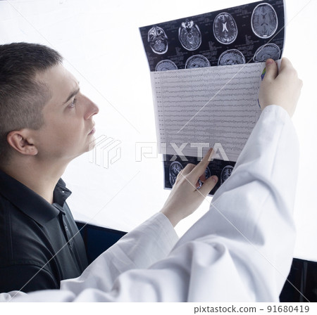 Epileptologist examines patient MRI and electroencephalogram. Concept treating epilepsy and helping people who suffer from this disease. Neurologist at work. Pathology of the brain. Seizure activity Epileptologist examines patient MRI and electroencephalogram. Concept treating epilepsy and helping people who suffer from this disease. Neurologist at work. Pathology of the brain. Seizure activity 91680419
