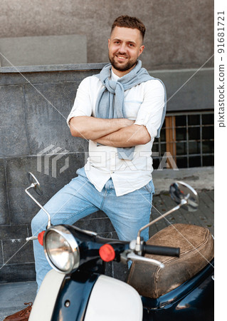 Portrait of a young and stylish man with a moped in summer sunny day in european city Portrait of a young and stylish man with a moped in summer sunny day in european city 91681721