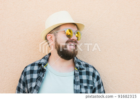 Bearded man portrait in summer clothes and hat stand over beige wall on street city urban and travel concept - copy space and empty space for advertising Bearded man portrait in summer clothes and hat stand over beige wall on street city urban and travel concept - copy space and empty space for advertising 91682315