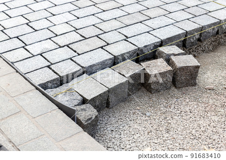 Construcion site of pavement granite cobblestone road in old city center installation or renovation repair. Roadworks stonework at pedestrian area. Paved sidewalk reconstruction. Urban development Construcion site of pavement granite cobblestone road in old city center installation or renovation repair. Roadworks stonework at pedestrian area. Paved sidewalk reconstruction. Urban development 91683410