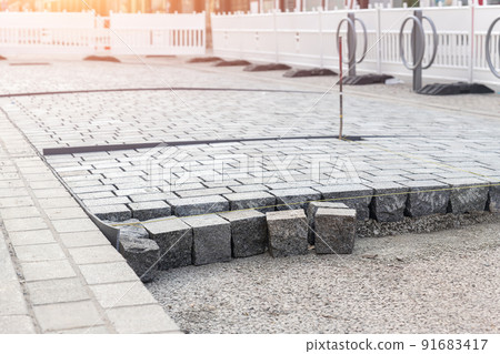 Construcion site of pavement granite cobblestone road in old city center installation or renovation repair. Roadworks stonework at pedestrian area. Paved sidewalk reconstruction. Urban development 91683417