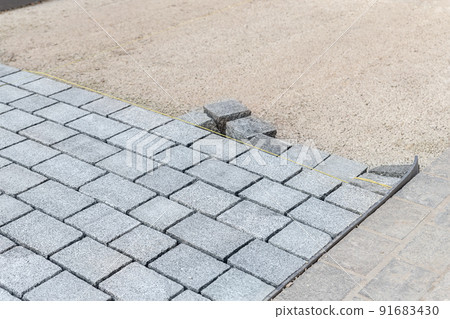 Construcion site of pavement granite cobblestone road in old city center installation or renovation repair. Roadworks stonework at pedestrian area. Paved sidewalk reconstruction. Urban development 91683430