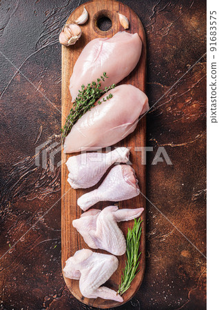 Raw chicken meat, assortment of parts - drumstick, breast fillet, wings, thigh with spices. Dark background. Top view 91683575