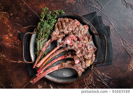 BBQ Grilled lamb chop steak, mutton rib cutlet in steel tray with thyme. Dark background. Top view BBQ Grilled lamb chop steak, mutton rib cutlet in steel tray with thyme. Dark background. Top view 91683589