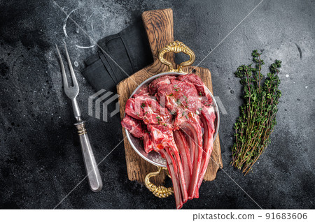 Lamb mutton chop steak, raw meat cutlet in a skillet with herbs. Black background. Top view 91683606