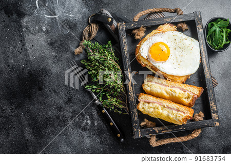 French toasts croque monsieur and croque madame with sliced ham, melted emmental cheese and egg. Black background. Top view. Copy space 91683754