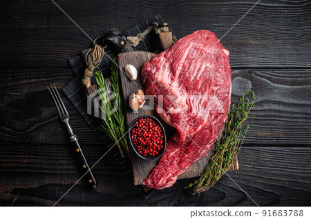 Tri Tip black angus beef steak on cutting board with herbs, raw meat. Black Wooden background. Top view 91683788