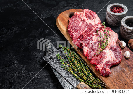 Butcher marbled meat Steaks on wooden cutting board, raw beef rib-eye steaks. Black background. Top view. Copy space Butcher marbled meat Steaks on wooden cutting board, raw beef rib-eye steaks. Black background. Top view. Copy space 91683805