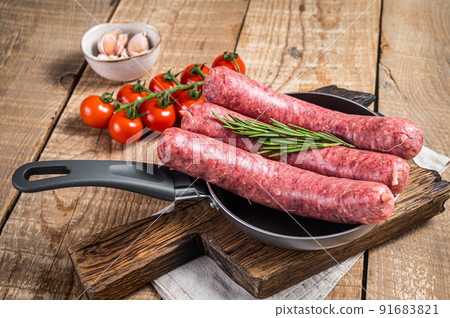 Raw sausages ready for cooking in a skillet, uncooked meat. Wooden background. Top view 91683821