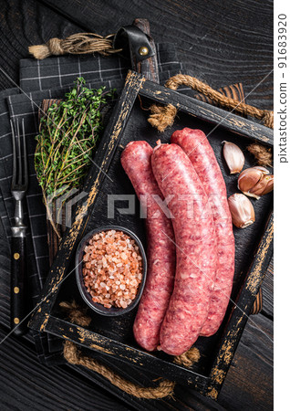 Raw sausages Bratwurst, fresh meat in wooden tray with thyme. Wooden background. Top view 91683920