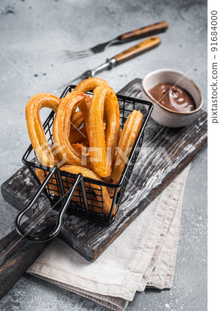 Traditional Spanish dessert churros with sugar and chocolate. Gray background. Top view Traditional Spanish dessert churros with sugar and chocolate. Gray background. Top view 91684000