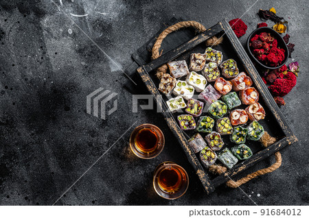 Turkish Delight Lukum, Oriental sweets with nuts and black tea. Black background. Top view. Copy space Turkish Delight Lukum, Oriental sweets with nuts and black tea. Black background. Top view. Copy space 91684012