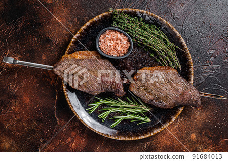 Brazilian BBQ - grilled dry aged picanha beef steak with herbs. Dark background. Top view 91684013
