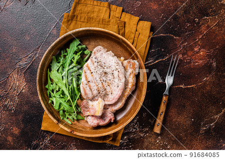 Roasted pork chop steaks or cutlets with arugula salad. Dark background. Top view 91684085
