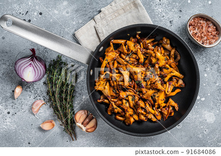 Fried chanterelle mushrooms with onions and thyme in a skillet. Gray background. Top view 91684086
