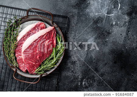 Raw top sirloin or Picanha beef meat steak in a steel tray. Black wooden background. Top view. Copy space 91684087