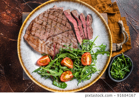 Diner with grilled beef veal meat steaks and vegetable salad. Dark background. Top view Diner with grilled beef veal meat steaks and vegetable salad. Dark background. Top view 91684167