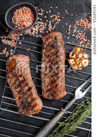 BBQ grilled Lamb tenderloin fillet meat on grill, mutton loin steak. Black background. Top view 91684191