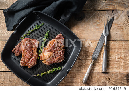 Grilled Chuck eye Roll beef steaks with herbs on grill skillet. Wooden background. Top view 91684249