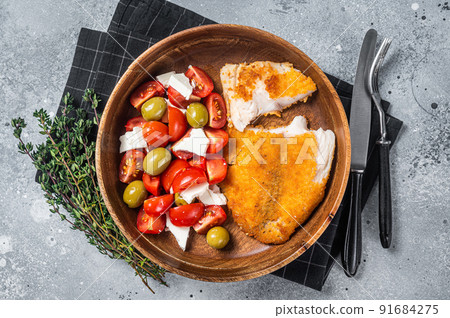 Fried tilapia fillet on a plate with salad. Gray background. Top view 91684275