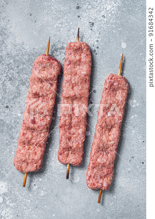 Raw Turkish Adana shish kebab on butcher table. Gray background. top view Raw Turkish Adana shish kebab on butcher table. Gray background. top view 91684342