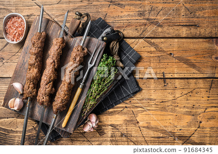 BBQ Grilled Adana kebab on skewers from minced lamb beef meat. Wooden background. Top view. Copy space 91684345