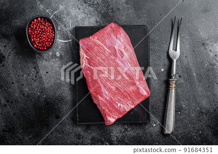 Prime choice flank steak, raw beef meat on marble board with herbs. Black background. Top view Prime choice flank steak, raw beef meat on marble board with herbs. Black background. Top view 91684351