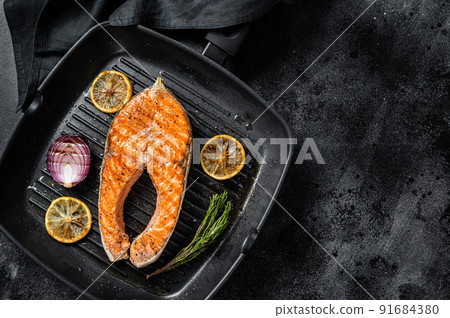 Salmon Fish Steak grilled on a grill pan with herbs. Black background. Top view. Copy space Salmon Fish Steak grilled on a grill pan with herbs. Black background. Top view. Copy space 91684380