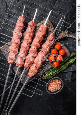 Raw Shish kebab from mince lamb and beef meat, turkish adana kebab on Skewers. Black background. Top view Raw Shish kebab from mince lamb and beef meat, turkish adana kebab on Skewers. Black background. Top view 91684410