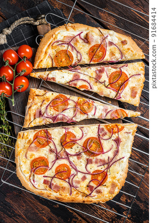 Traditional German pie Flammkuchen or tarte flambee with cream cheese, bacon, tomato and onions. Wooden background. Top view 91684414
