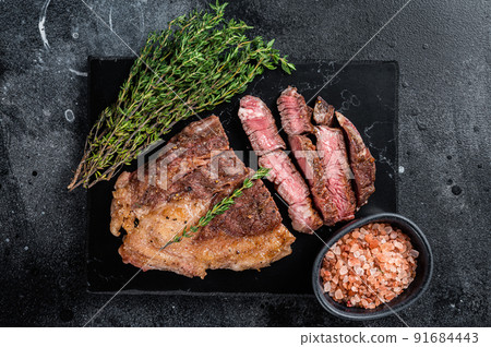 Roasted bbq Chuck Roll beef steaks with herbs. Black background. Top view 91684443