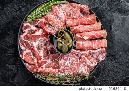 Italian Antipasto set platter, cured meat plate with Prosciutto crudo, Salami and Coppa Sausage. Black background. Top view 91684448