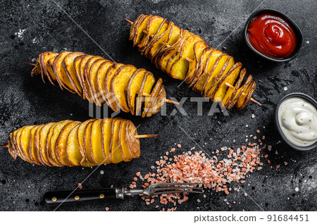 Roasted Tornado or twisted potatoes with ketchup sauce. Black background. Top view 91684451