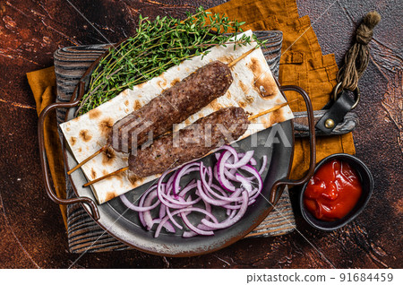 Turkish Adana Kebab from mince lamb beef meat on Skewer with flatbread and onion. Dark background. Top view 91684459