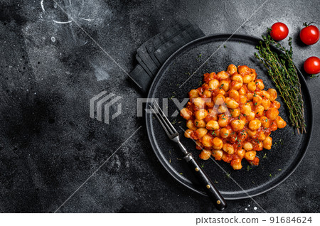 Portion of Italian Gnocchi potato pasta with tomato sauce. Black background. Top view. Copy space 91684624