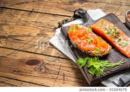 Sandwich toast with Salted salmon fillet, herbs on a wooden board. Wooden background. Top view. Copy space Sandwich toast with Salted salmon fillet, herbs on a wooden board. Wooden background. Top view. Copy space 91684676