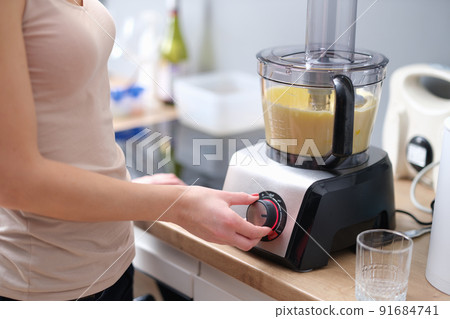Woman presses start of food processor with dough 91684741