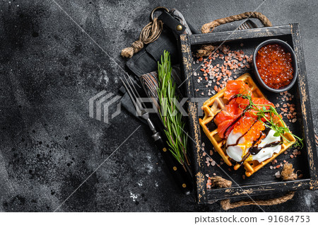 Delicious Waffle with smoked salmon fillet, poached egg and red caviar. Black background. Top view. Copy space 91684753