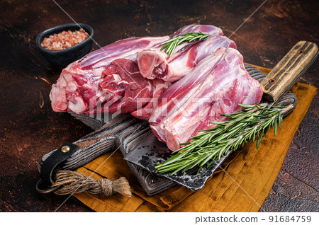 Uncooked Raw lamb mutton shanks on a butcher board. Dark background. Top view 91684759