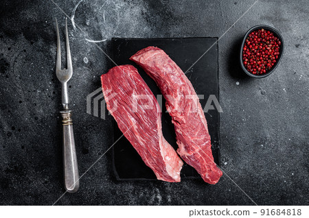 Bavette raw beef meat steak or Sirloin flap on marble board. Black background. Top view Bavette raw beef meat steak or Sirloin flap on marble board. Black background. Top view 91684818