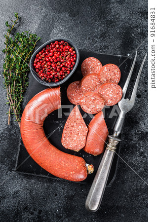 Turkish Sliced Sucuk meat sausage on a marble board with thyme. Black background. Top view 91684831