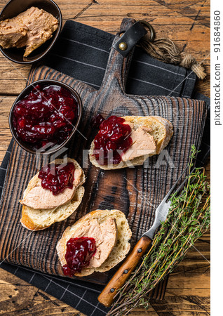 French cuisine Foie gras toasts, goose liver pate and lingonberry marmalade. wooden background. Top view French cuisine Foie gras toasts, goose liver pate and lingonberry marmalade. wooden background. Top view 91684860
