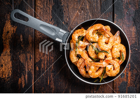 Fried with butter and garlic prawns shrimps in a skillet. Wooden background. Top view Fried with butter and garlic prawns shrimps in a skillet. Wooden background. Top view 91685201